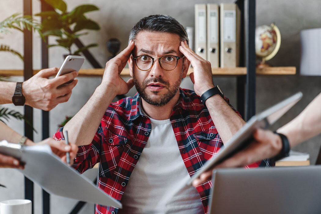 Psychische klachten onder werkenden nemen toe. Vermoeide werkende persoon achter bureau die stress ervaart en behoefte heeft aan rust en wandelen in de natuur.